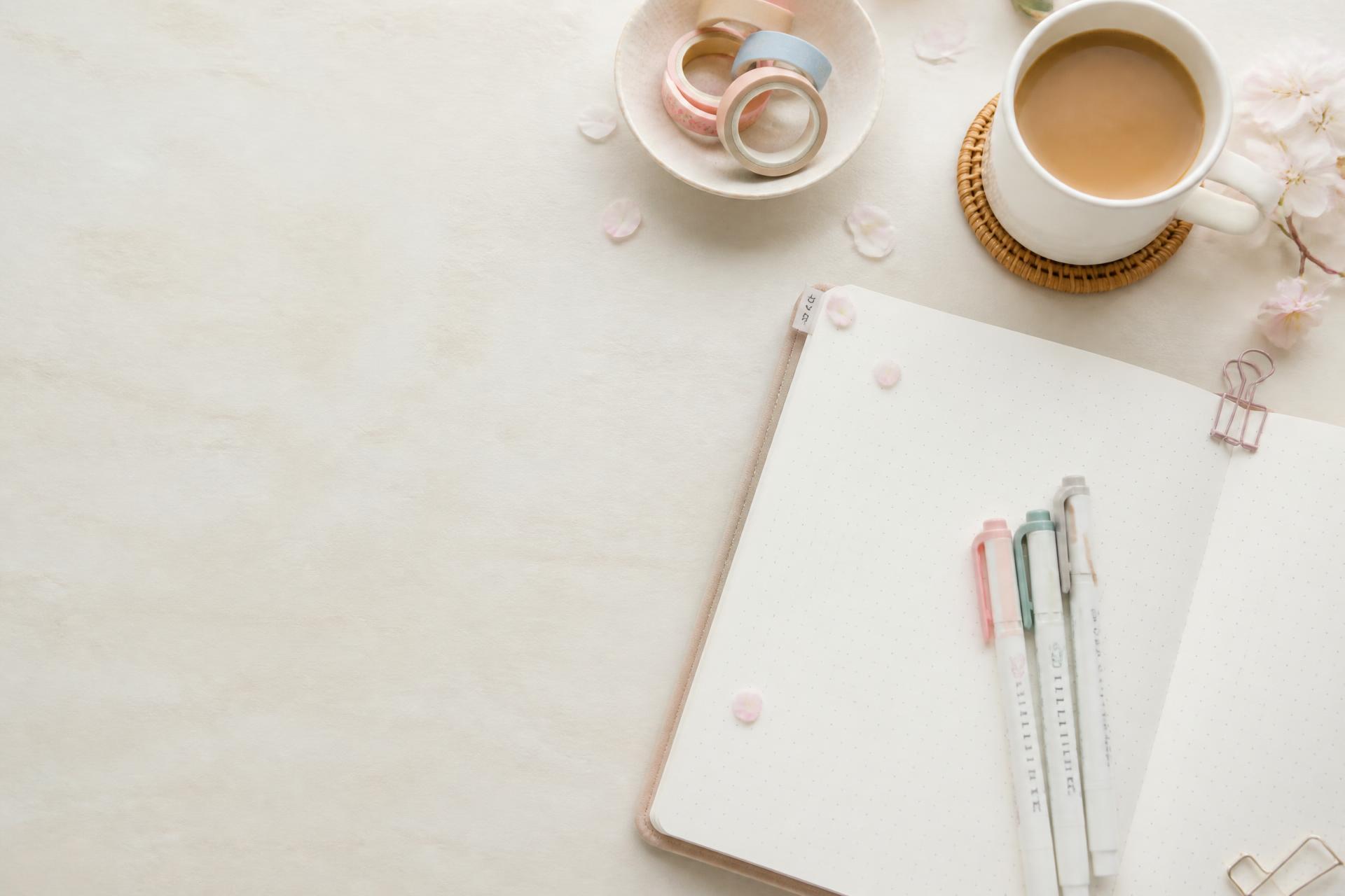 Japanese stationery on a softly lit desk with a dot-grid notebook, pastel pens and washi tape